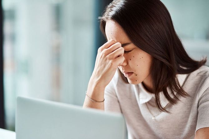 仕事中、疲れて目頭を押さえる女性