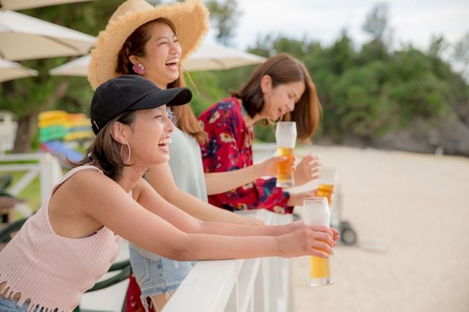 夕暮れのビーチでビール片手に楽しむ女性たち