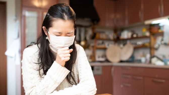 マスクを着用して咳をする女性