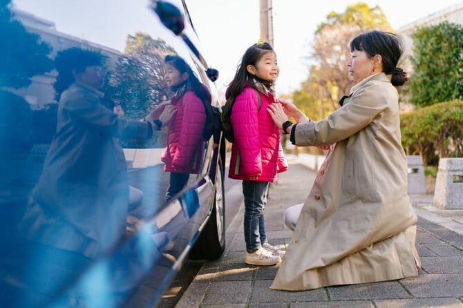 娘にジャケットを着せる出勤前の母親