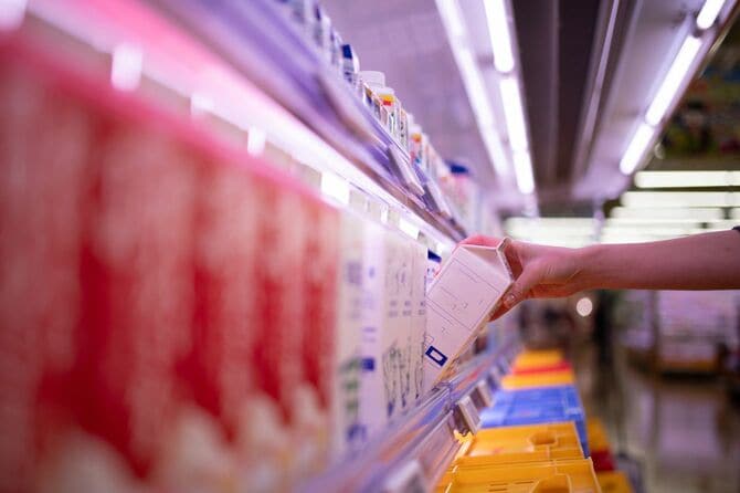 スーパーで牛乳を手に取る女性