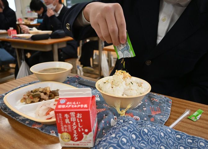 給食のご飯に、持参したふりかけをかける中学生