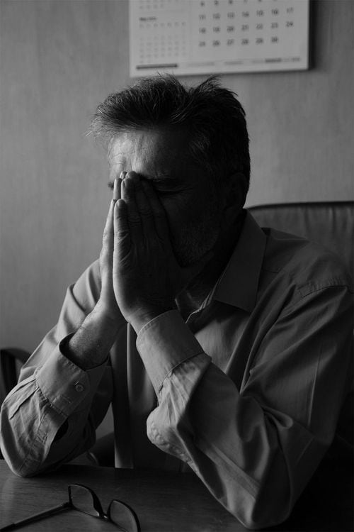 手で顔を覆っている男性