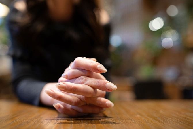 テーブルの上に手を組んだ女性