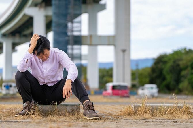 空き地に座り込み頭を抱える男性