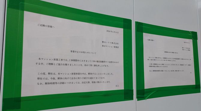 マンション前に貼られた2枚の張り紙。「事業中止のお知らせについて」(6月6日付)と「建物解体に向けた準備のお知らせ」(6月7日付)