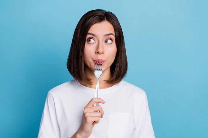 フォークをくわえた女性