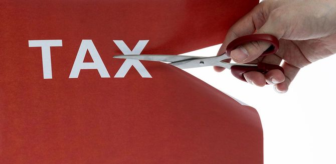 「TAX」と書かれた紙をハサミで切る人の手