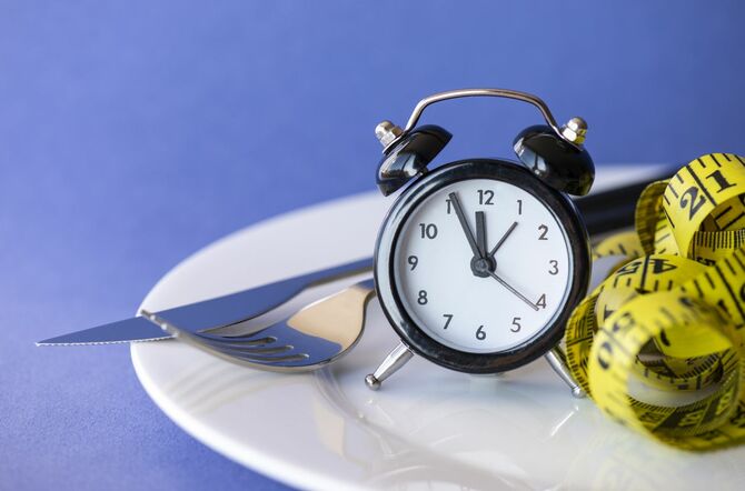 目覚まし時計、フォーク、スプーン付きの空のプレート