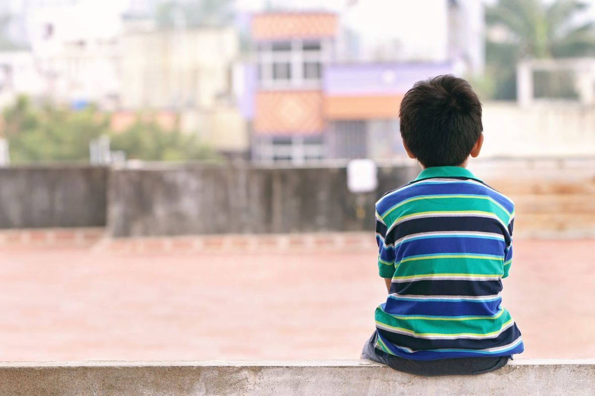 壁の上に座って遠くを眺める少年