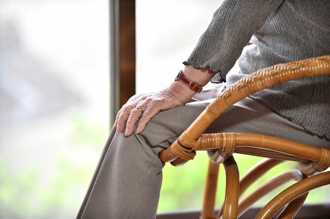 窓辺の籐椅子に座ってのんびり外を眺める日本の高齢女性
