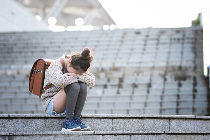 ランドセルを背負ったまま、階段で泣いている女の子