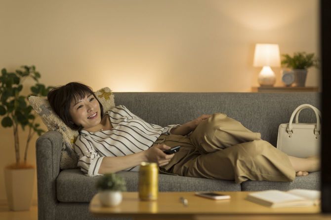 ソファに横になり、テレビを見ている女性