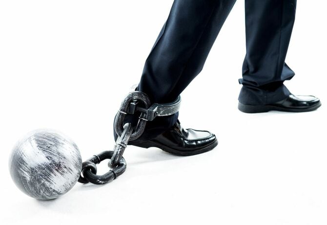鉄球と鎖が足に付けられたビジネスパーソン
