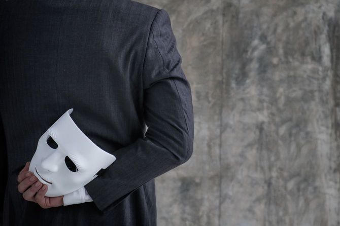 白いマスクを手に持ったビジネスマン