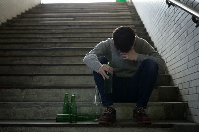 地下に続く階段に座り込んで俯いている人