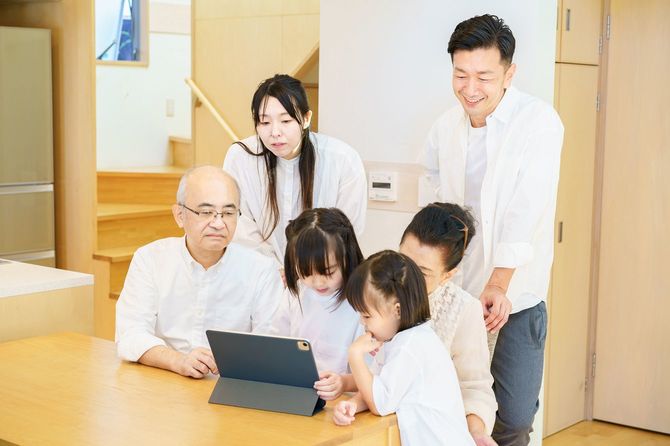 タブレット端末の周りに集まる3世代の家族