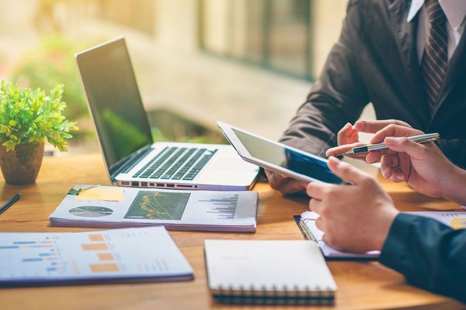 資料を広げ、パソコンやタブレットでデータの分析をする人