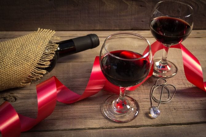 グラスに注がれた赤ワインとは別に包装を解かれたワインボトル