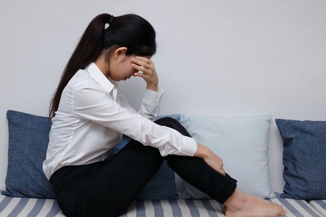 ソファに体育座りで静かに泣いている女性