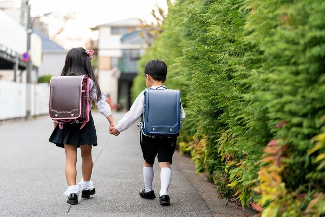 手をつないで一緒に学校に歩いている小学生のきょうだい