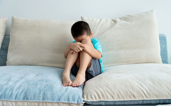 ソファに座っている悲しい少年