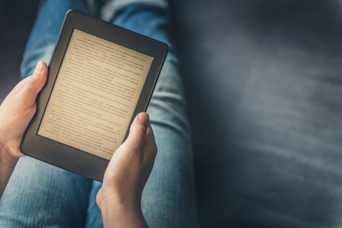 ソファーに座り、Kindle電子書籍リーダーで書籍を読んでいる女性の手元