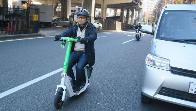 ヘルメットを装着して電動スクーターに乗る筆者