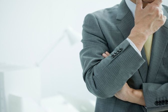 顎に手を当てて考えるビジネスマン