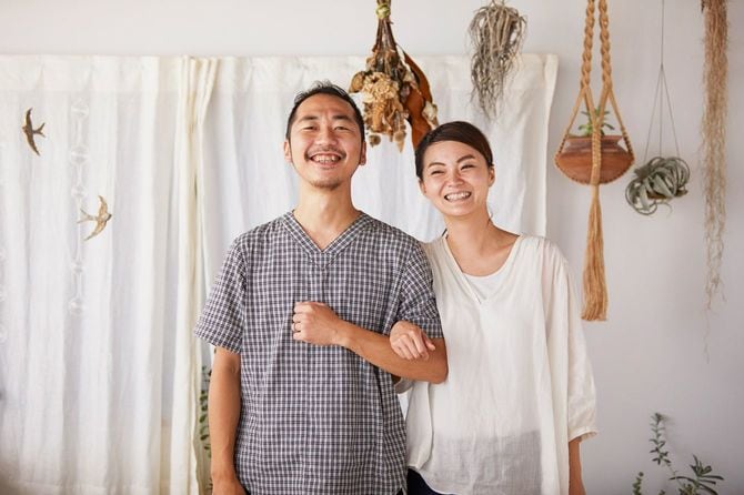 室内で腕を組み、笑顔で写真に納まるカップル