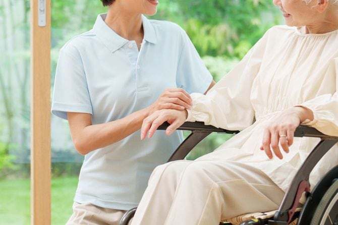 車椅子に乗る年配の女性と介護者