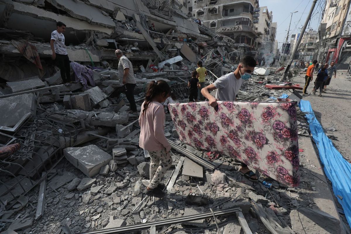2023年10月8日、ガザ市でイスラエルの空爆により破壊されたアル・アクルーク・タワーの廃墟を視察するパレスチナ人