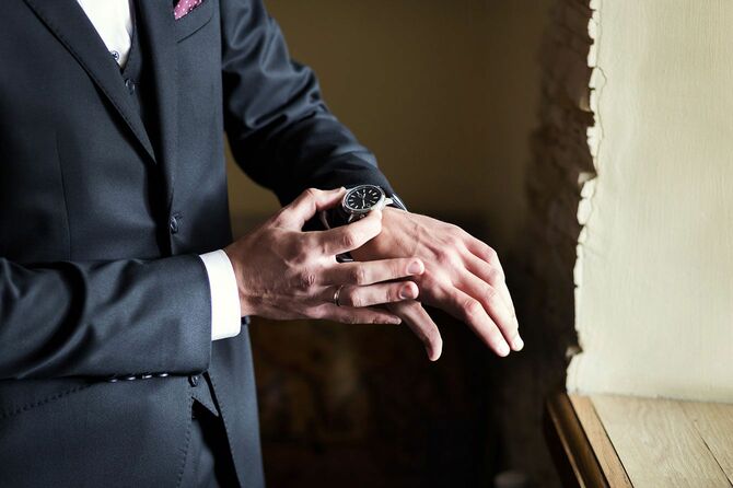 腕時計を確認するスーツの男性