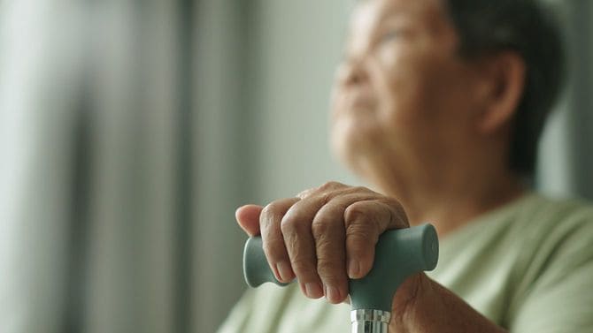 自宅で杖を持つ高齢者