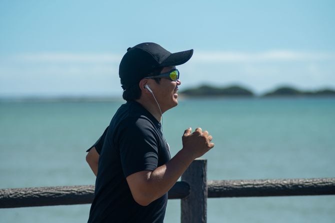 海のそばを走る道で楽しんでいる日本人男性。