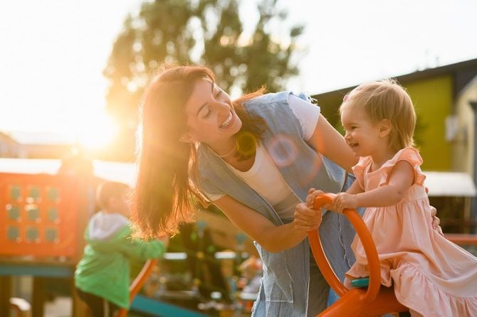 公園の遊具で遊ぶ子供と支えている母親