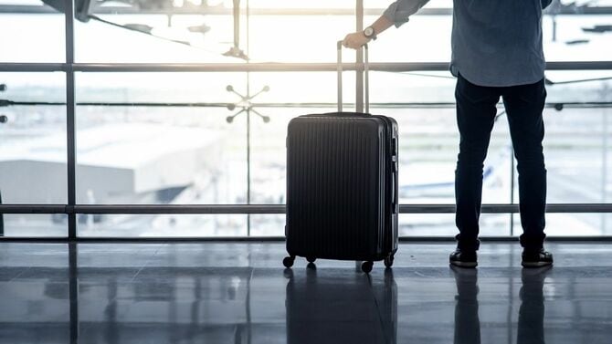 空港でスーツケースの荷物を持っている男