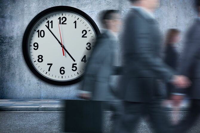 時計を過ぎて歩いていくビジネスマン