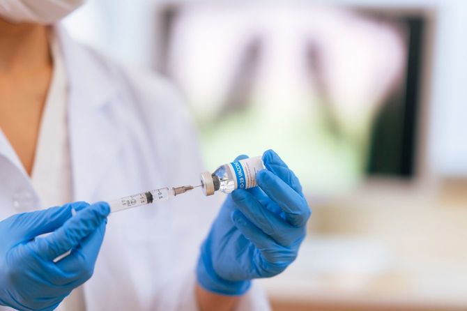 ワクチンをバイアルから注射器で吸う医師の手