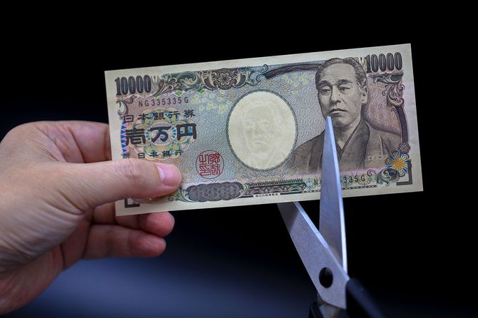 1万円札をはさみで切ろうとする人