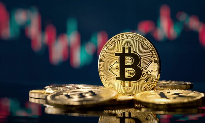 株価チャートを背景にビットコインの硬貨