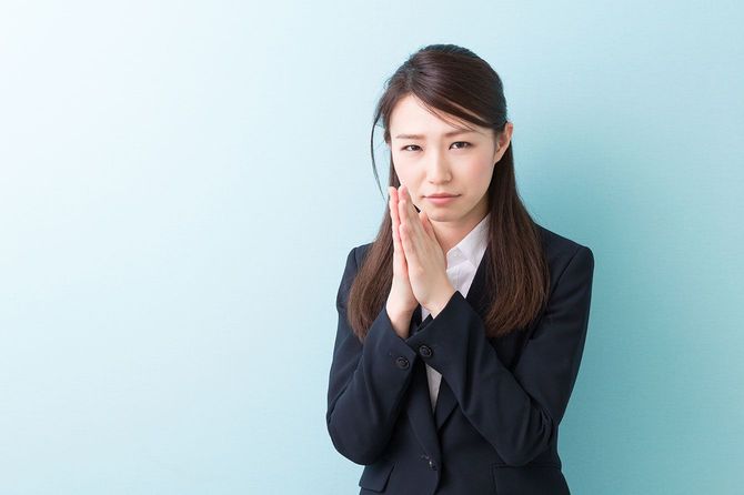 お願いするように手を合わせる女性