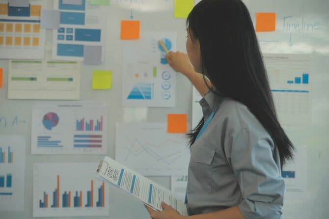 壁に貼られた資料を説明するビジネスウーマン