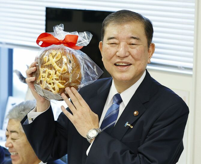 自民党総裁選の選対会合で、「必勝」パンを手に笑顔を見せる石破茂氏＝2024年9月27日午前8時35分、国会