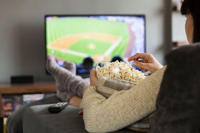 ポップコーンを食べながらテレビの野球中継を見る人