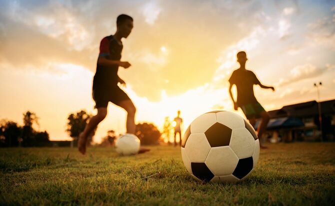 ダートフィールドでサッカーサッカーを楽しんでいる子供たちのグループの屋外アクションスポーツ