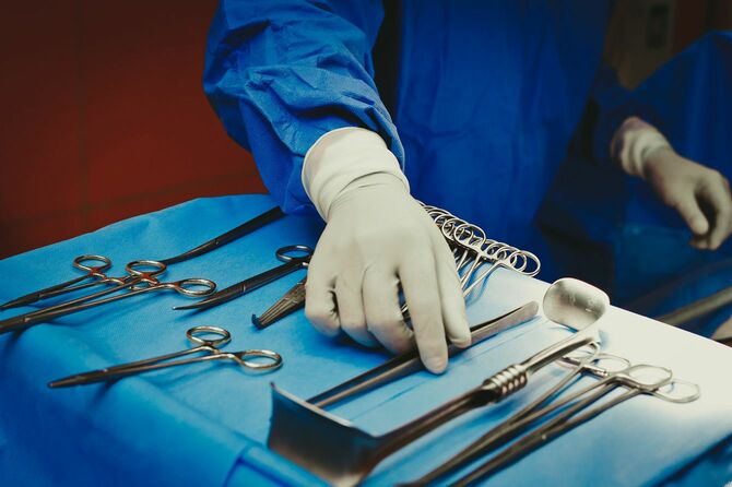 テーブルに並べられた手術器具を手に取る医師