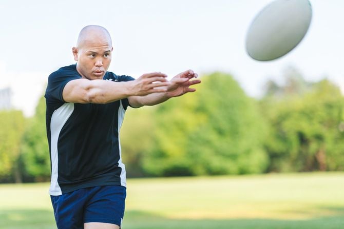 ラグビーボールをチームメイトにパスする選手
