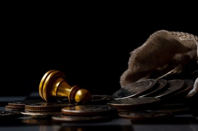 チェスはコインの山に落ちる。ビジネスの困難と倒産コンセプトのための暗い色調。