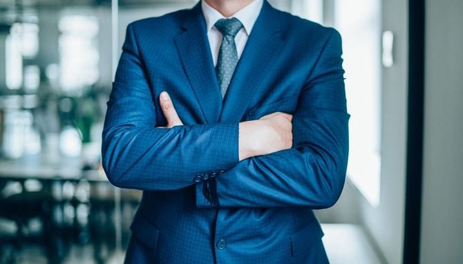 腕を組んでいるガタイのいいビジネスマン